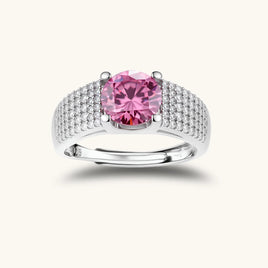 Adjustable sterling silver ring with round pink moissanite center stone and pavé crystal detailing on cream background.