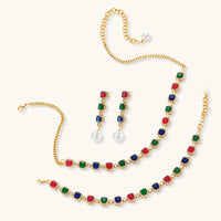 Multicolor zirconia necklace, bracelet and pearl drop earrings arranged on a light background | Olaty