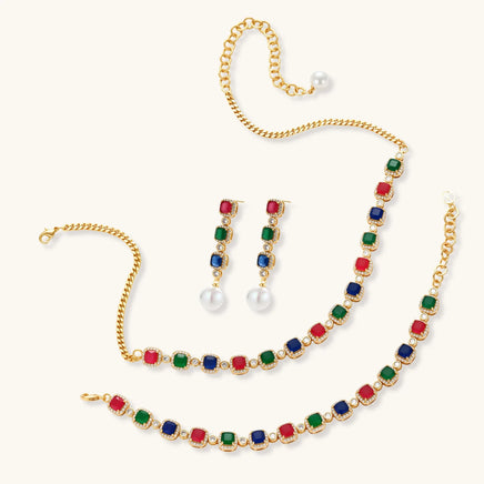 Multicolor zirconia necklace, bracelet and pearl drop earrings arranged on a light background | Olaty