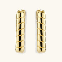 Chunky segmented gold-plated huggie hoop earrings with bamboo-inspired geometric design on white background.