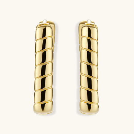Chunky segmented gold-plated huggie hoop earrings with bamboo-inspired geometric design on white background.