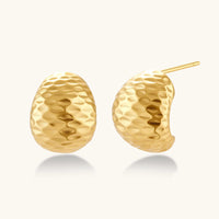 Pair of textured gold-plated sterling silver huggie earrings with dimpled surface finish on cream background.