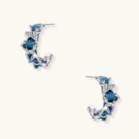 Blue denim sculptural wave hoop earrings with polished silver-tone organic frames | Olaty