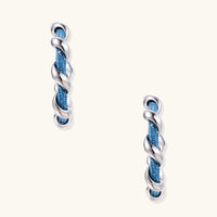 Front view of blue denim hoop earrings with twisted silver-tone metal wrapping and slim sculptural profile | Olaty