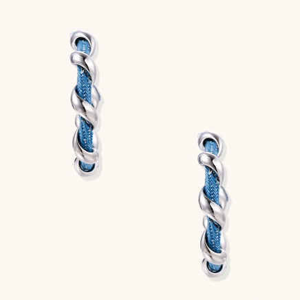 Front view of blue denim hoop earrings with twisted silver-tone metal wrapping and slim sculptural profile | Olaty