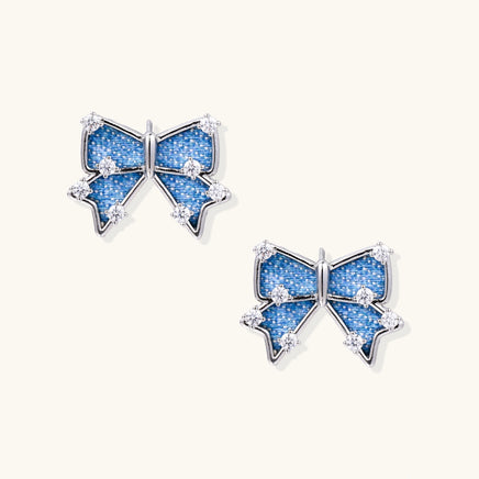 Blue denim bow stud earrings with silver-tone frames and clear zirconia accents | Olaty