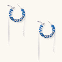 Angled view of denim hoop earrings featuring blue and white woven fabric, silver-tone chain wrapping and long chain drops | Olaty