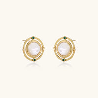 Circular gold stud earrings with iridescent mother-of-pearl center and green zirconia accents on cream background.