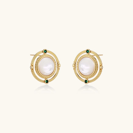 Circular gold stud earrings with iridescent mother-of-pearl center and green zirconia accents on cream background.