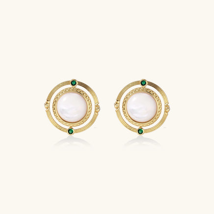 Circular gold stud earrings with iridescent mother-of-pearl center and green zirconia accents on cream background.