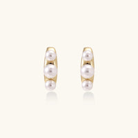 14K gold-plated curved stud earrings with three white freshwater pearls aligned vertically on cream background