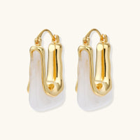 Liquid curve white resin hoop earrings with polished gold-tone frames, angled pair view | Olaty