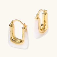 Liquid curve white resin hoop earrings showing sculptural gold-tone sides and closures | Olaty