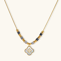 Gold-tone necklace with grey stone beads and iridescent clover-shaped shell pendant, front close-up | Olaty