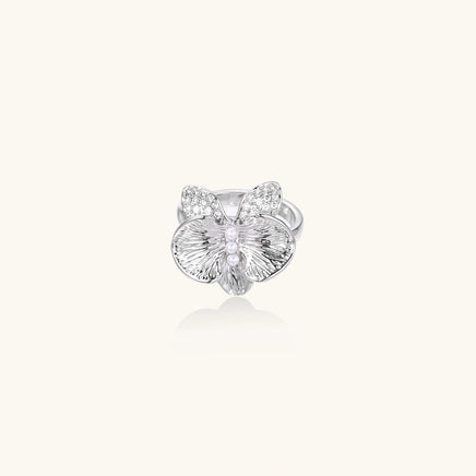 Silver-toned orchid ring with textured petals, pearl center accents, and sparkling zirconia stones on white background.