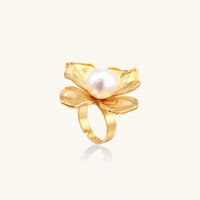 Gold-plated flower ring with textured petals and white cotton pearl center on cream background