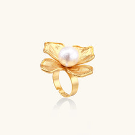 Sculptural four-petal flower statement ring with textured gold-tone petals and central white pearl, angled view | Olaty