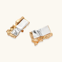 Close-up of matching two-tone abstract statement earrings with flowing gold and silver sculptural surfaces | Olaty