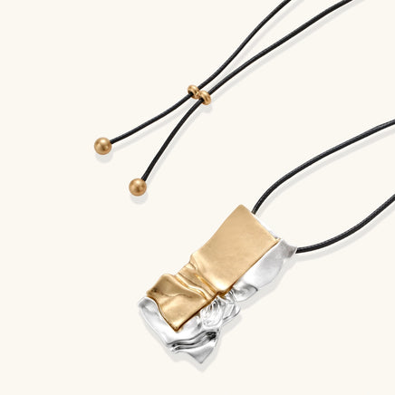 Two-tone sculptural pendant necklace on black adjustable cord with gold-tone end details | Olaty