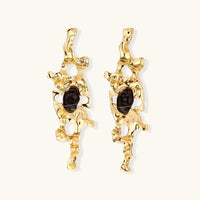 Gold-tone abstract statement earrings with organic cutouts and dark resin center accents | Olaty