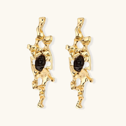 Front view of gold-tone liquid flow statement earrings with dark resin centers and irregular cutouts | Olaty
