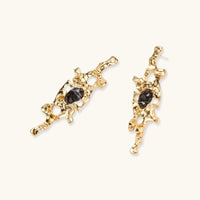 Angled view of sculptural gold-tone earrings with glossy dark resin accents and organic openwork design | Olaty