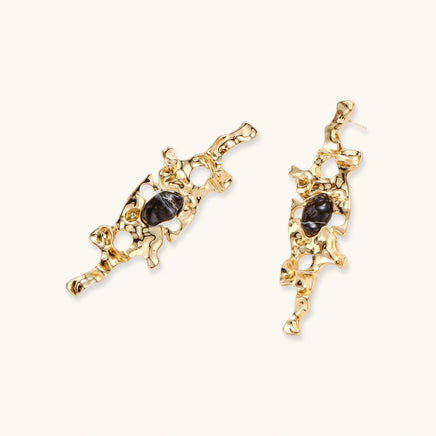 Angled view of sculptural gold-tone earrings with glossy dark resin accents and organic openwork design | Olaty