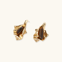 Angled view of sculptural gold-tone earrings with flowing irregular forms and polished brown gemstones | Olaty