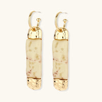 Gold-tone hoop drop earrings with cream marbled resin columns shown from an angled rear view | Olaty