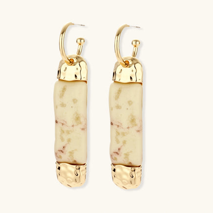 Gold-tone hoop drop earrings with cream marbled resin columns shown from an angled rear view | Olaty