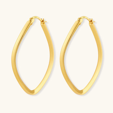 Set of geometric gold-plated sterling silver hoop earrings in oval and cushion shapes on cream background