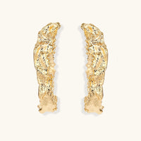 Front view of gold-tone statement hoop earrings with organic textured surface and curved silhouette | Olaty