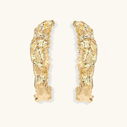 Front view of gold-tone statement hoop earrings with organic textured surface and curved silhouette | Olaty
