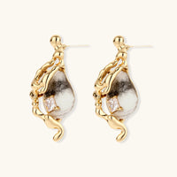 Side view of flowing gold-tone serpent earrings with marbled resin drops, zirconia accents and visible posts | Olaty
