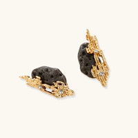Angled view of textured gold-tone earrings with dark resin centers and sparkling rhinestone details | Olaty