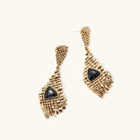 Angled view of architectural gold-tone drop earrings with woven grid texture and black resin accents | Olaty