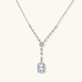 Sterling silver Y-necklace with rectangular moissanite pendant in halo setting and cascading accent stones on white background.