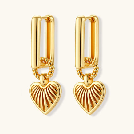 Gold-plated huggie earrings with textured heart charms featuring radiating sunburst patterns on white background.