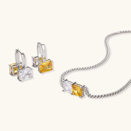 Angled view of necklace and drop hoop earrings with clear and golden yellow square zirconia stones | Olaty
