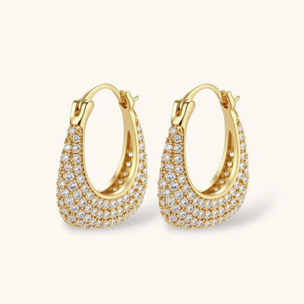 Gold-plated hoop earrings fully covered in sparkling zircon crystals with hinged closure on neutral background