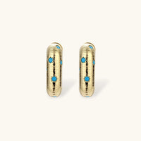 Gold-plated huggie hoop earrings with blue star inlays and textured surface, shown against white background.