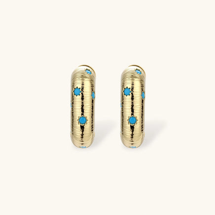 Gold-plated huggie hoop earrings with blue star inlays and textured surface, shown against white background.