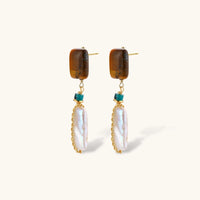 Angled view of amber-tone stone and elongated baroque pearl drop earrings with visible posts | Olaty