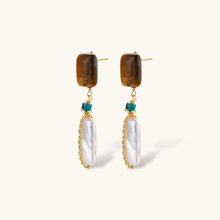 Angled view of amber-tone stone and elongated baroque pearl drop earrings with visible posts | Olaty