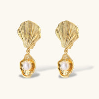 Angled view of sculptural scallop shell earrings with dangling freshwater pearl drops | Olaty