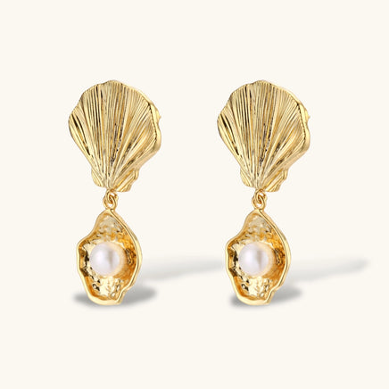 Angled view of sculptural scallop shell earrings with dangling freshwater pearl drops | Olaty