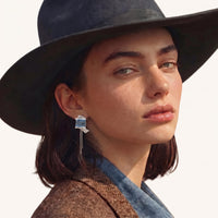Denim fringe chain statement earring worn with blue fabric panels, silver-tone details and long chain drops | Olaty