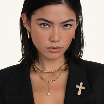 Divine Grace Zirconia Cross Brooch styled on a black blazer with layered gold necklaces | Olaty