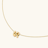 Angled view of polished gold initial N pendant necklace on a delicate adjustable chain | Olaty