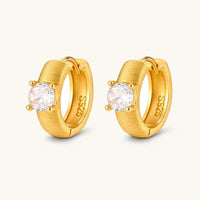Angled pair of brushed solitaire huggie hoop earrings with round cubic zirconia stones and hinged closures | Olaty
